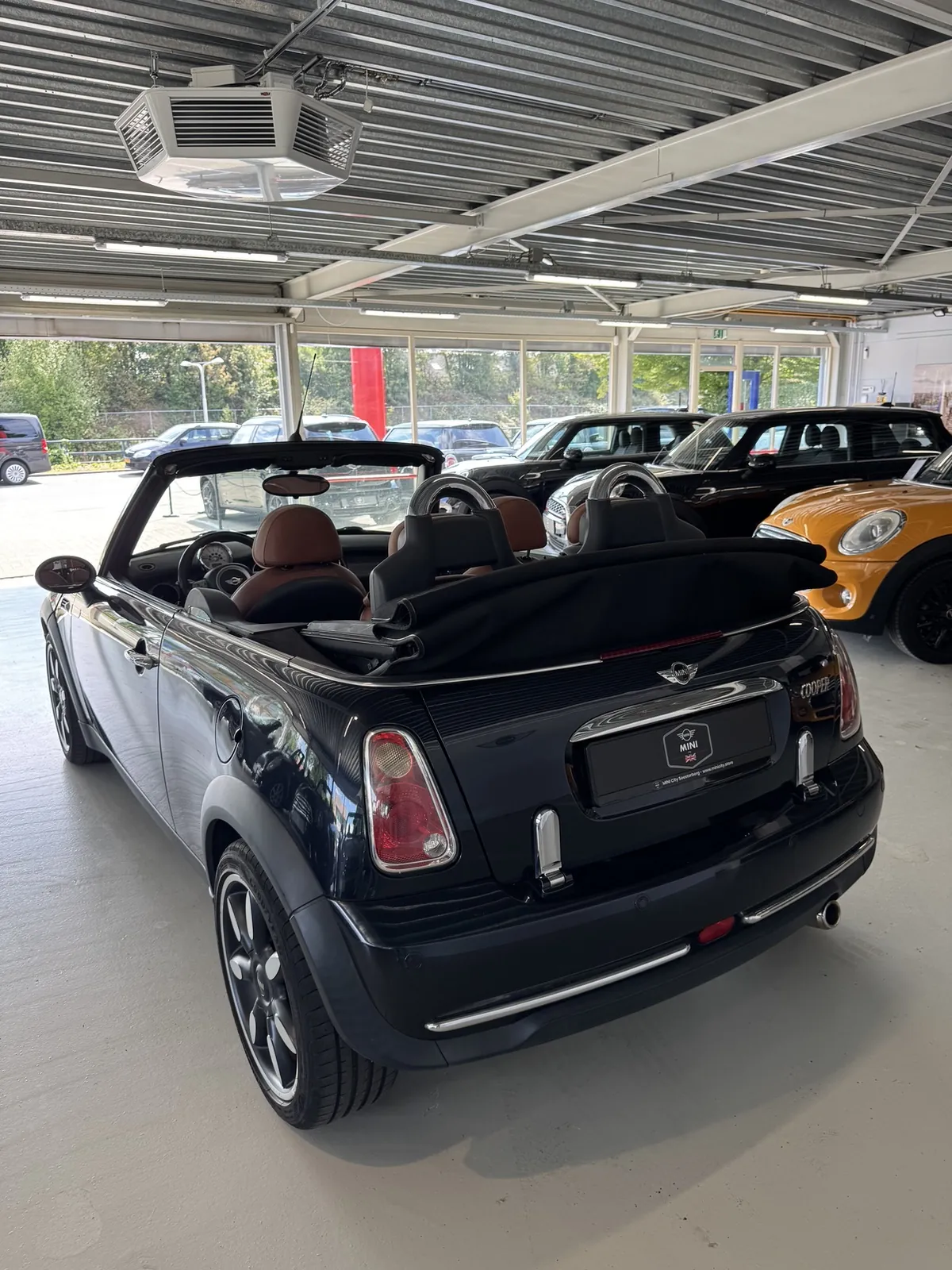 MINI Cabrio 2007 in zwart, driekwart achter met kap open, ander standpunt