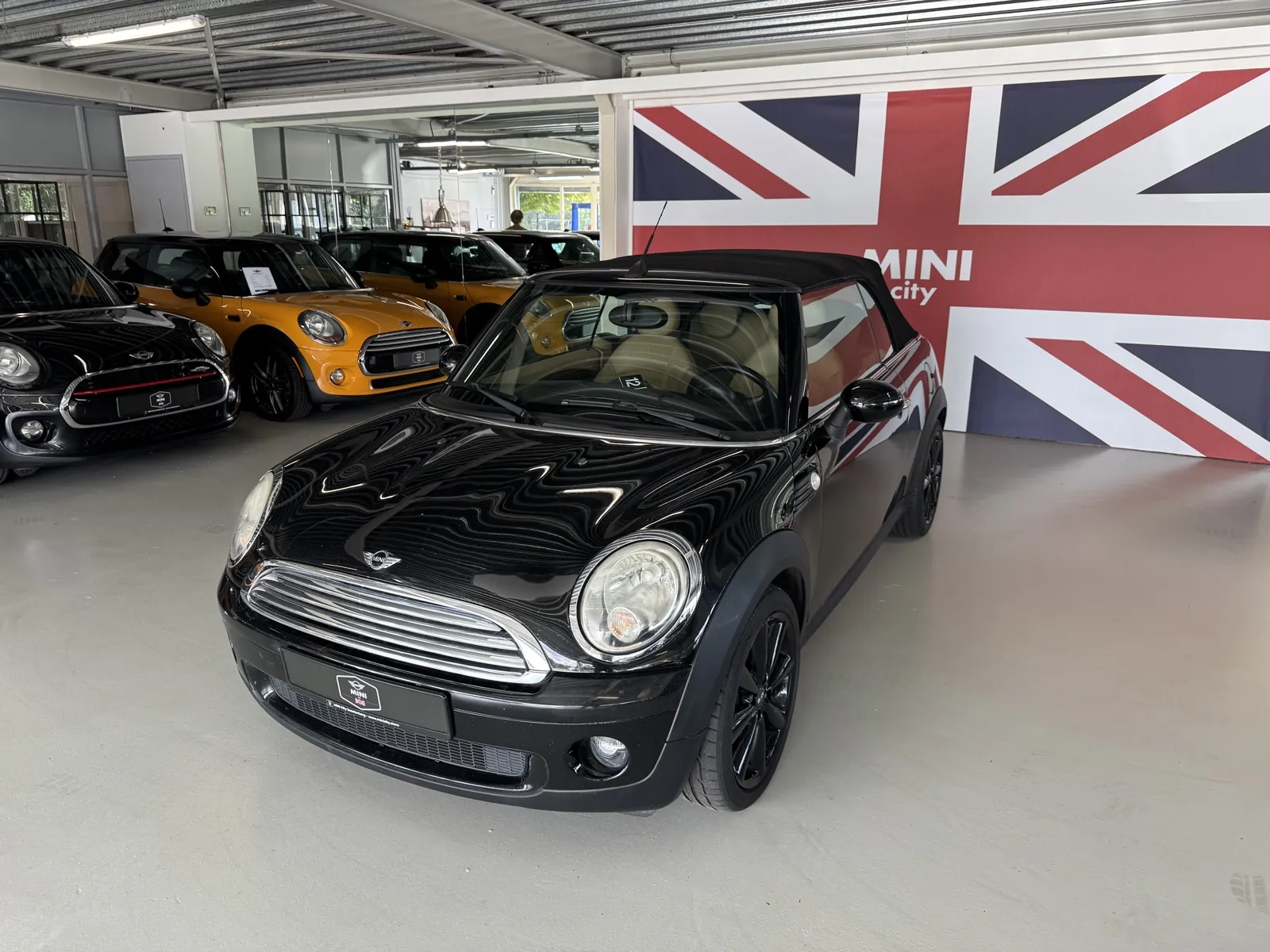 MINI Cooper Cabrio 2009 in zwart, driekwart voor, kap dicht, ander standpunt